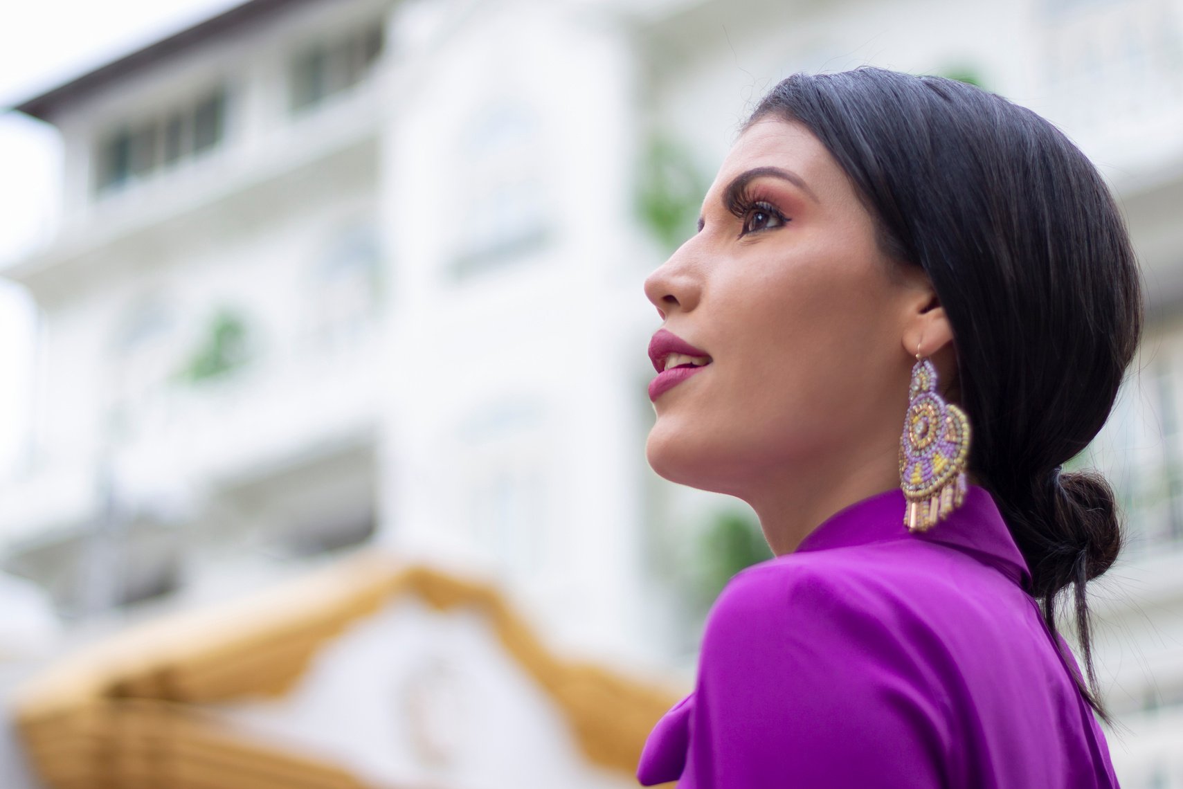 A Woman in Purple Shirt Wearing Purple and Gold Earrings